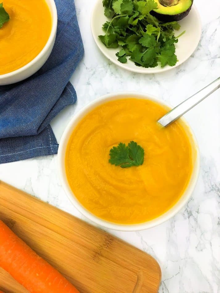 carrot cauliflower soup in bowl with sage and spoon
