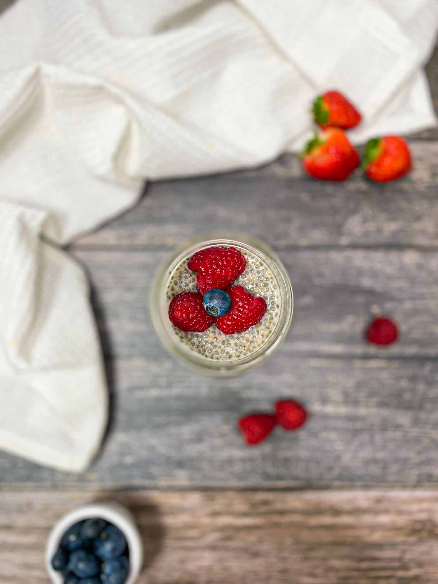 overhead view of glass jar with chia pudding inside and berries on top