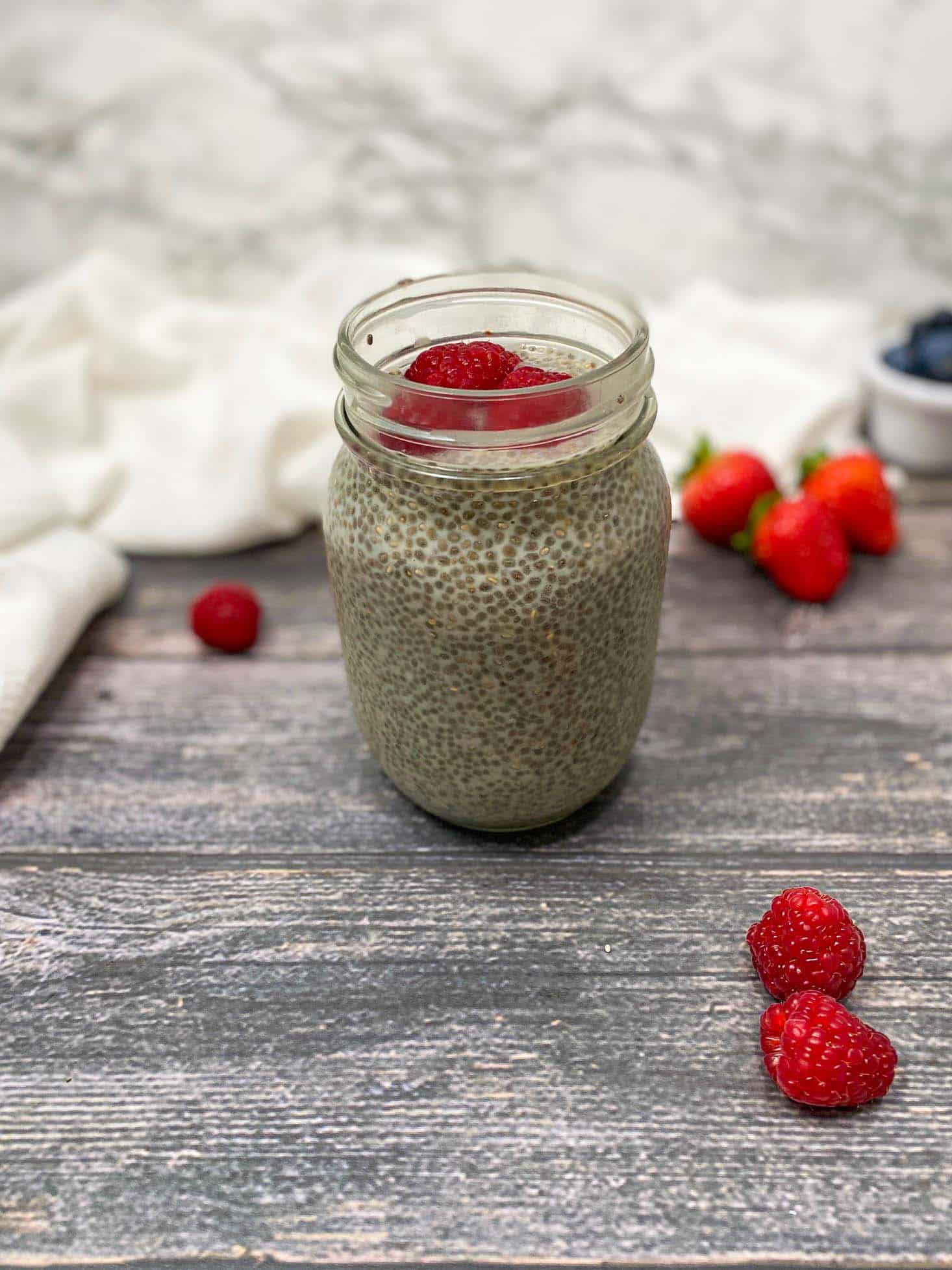 chia pudding in glass jar with raspberries on top