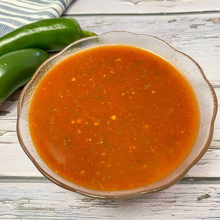 red sauce in glass bowl with jalapenos behind