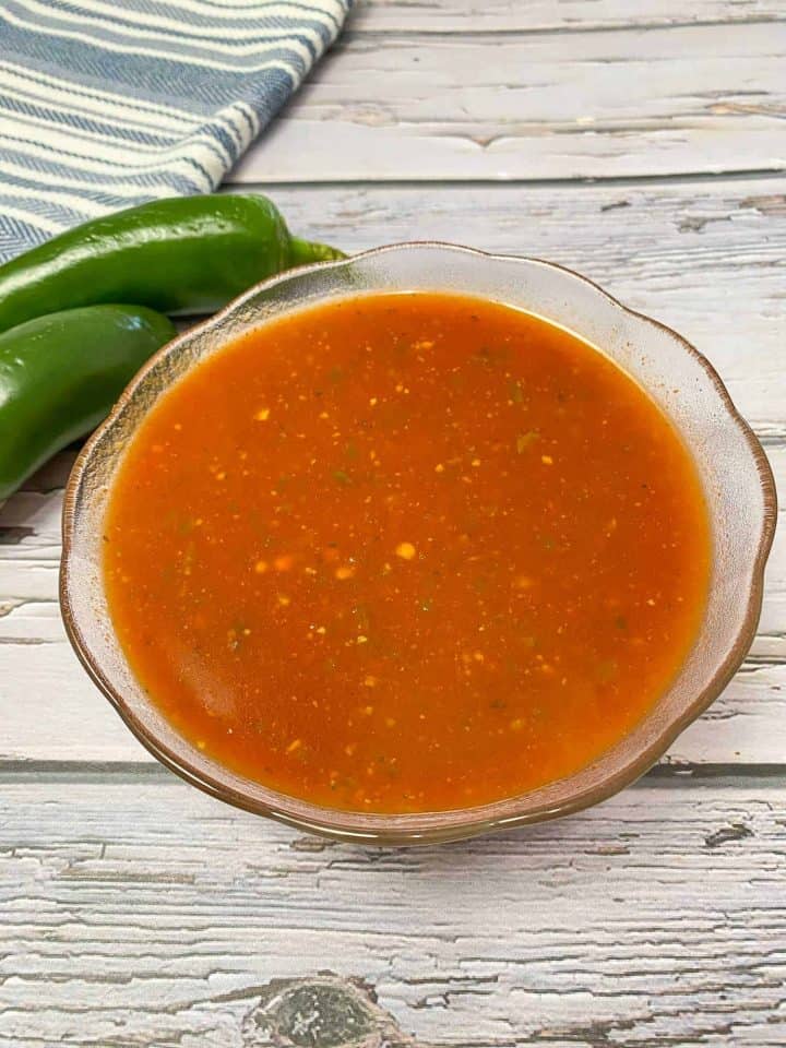 red sauce in glass bowl with jalapenos behind