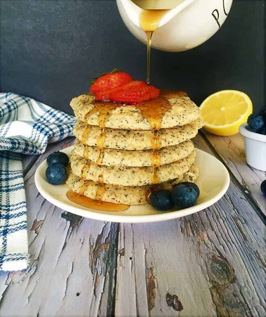 stack of pancakes with maple syrup being poured on top