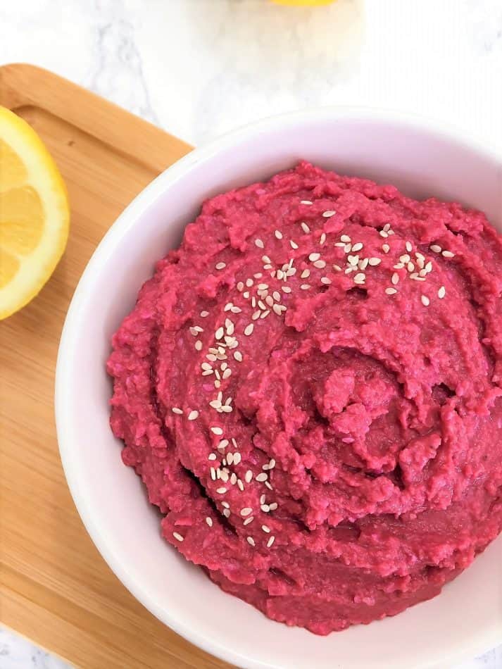 beet hummus in bowl garnished with sesame seeds