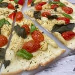 pizza sliced in triangles with tomato, basil and cheese