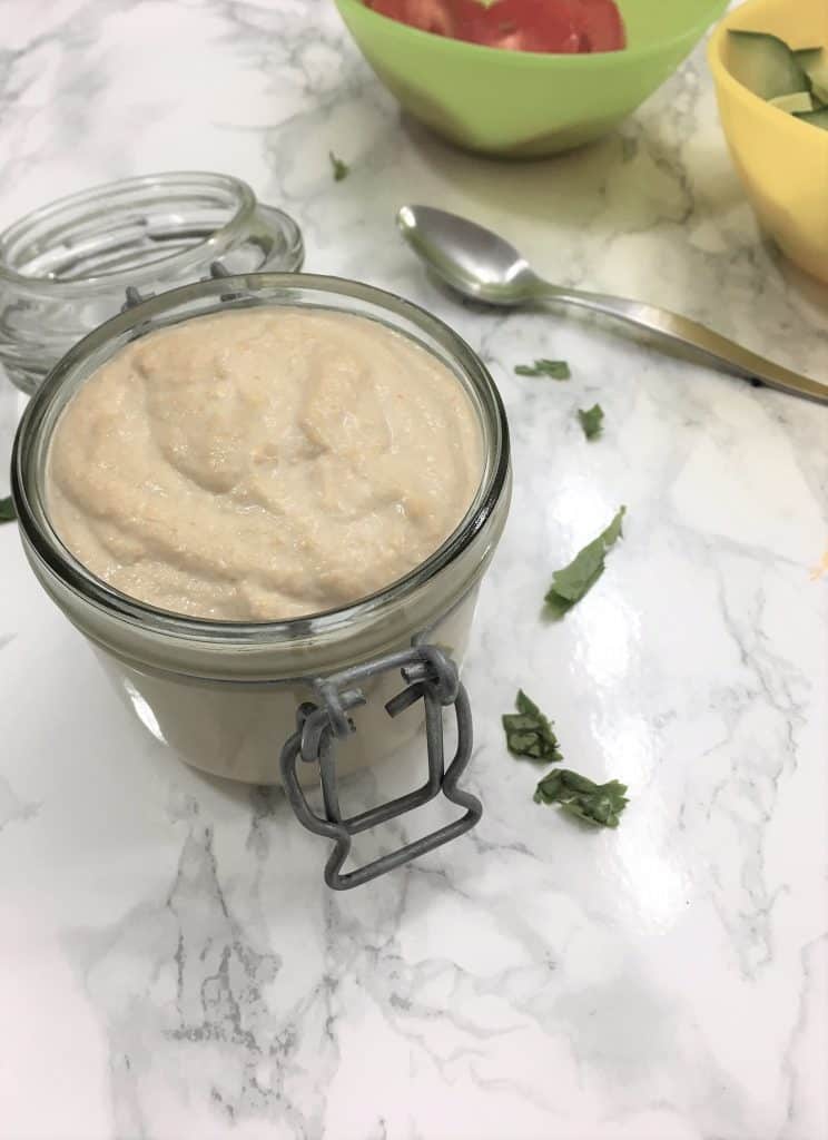 homemade tahini with tomatoes and cucumber in background