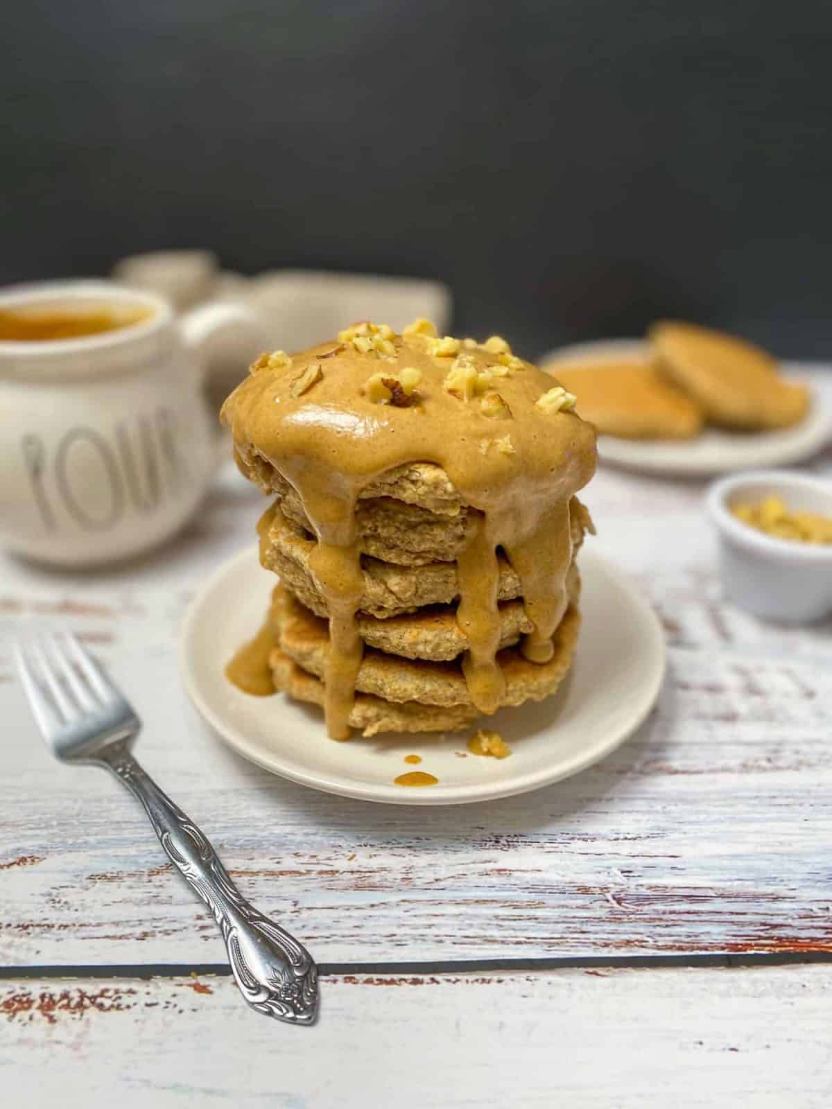stack of pancakes with peanut butter caramel on top and dripping down the sides