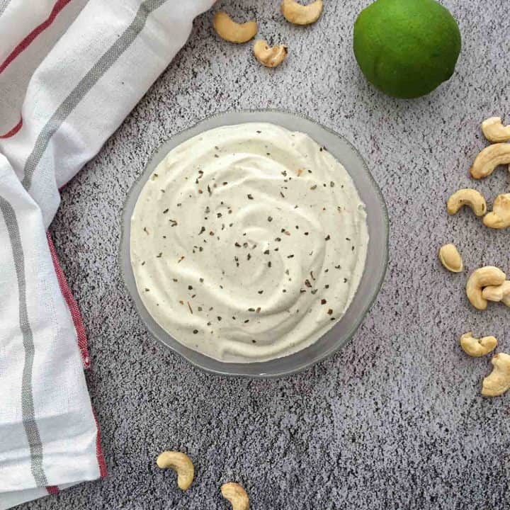 vegan ranch dressing in glass bowl with cashews scattered around it