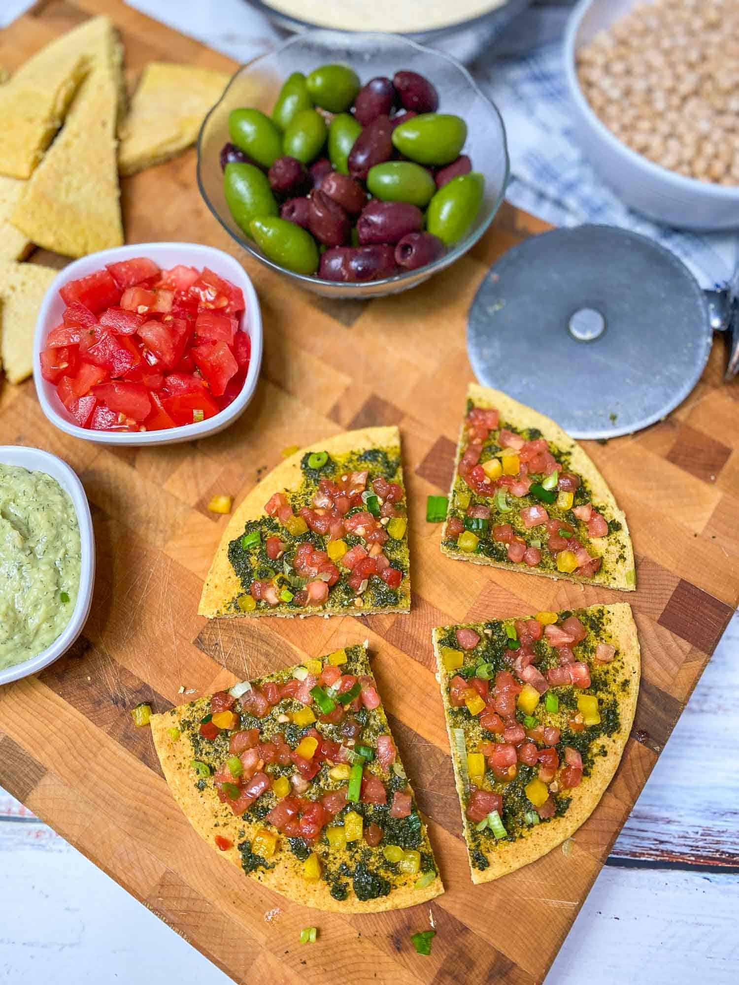 chickpea flatbread pizza cut into four slices on cutting board