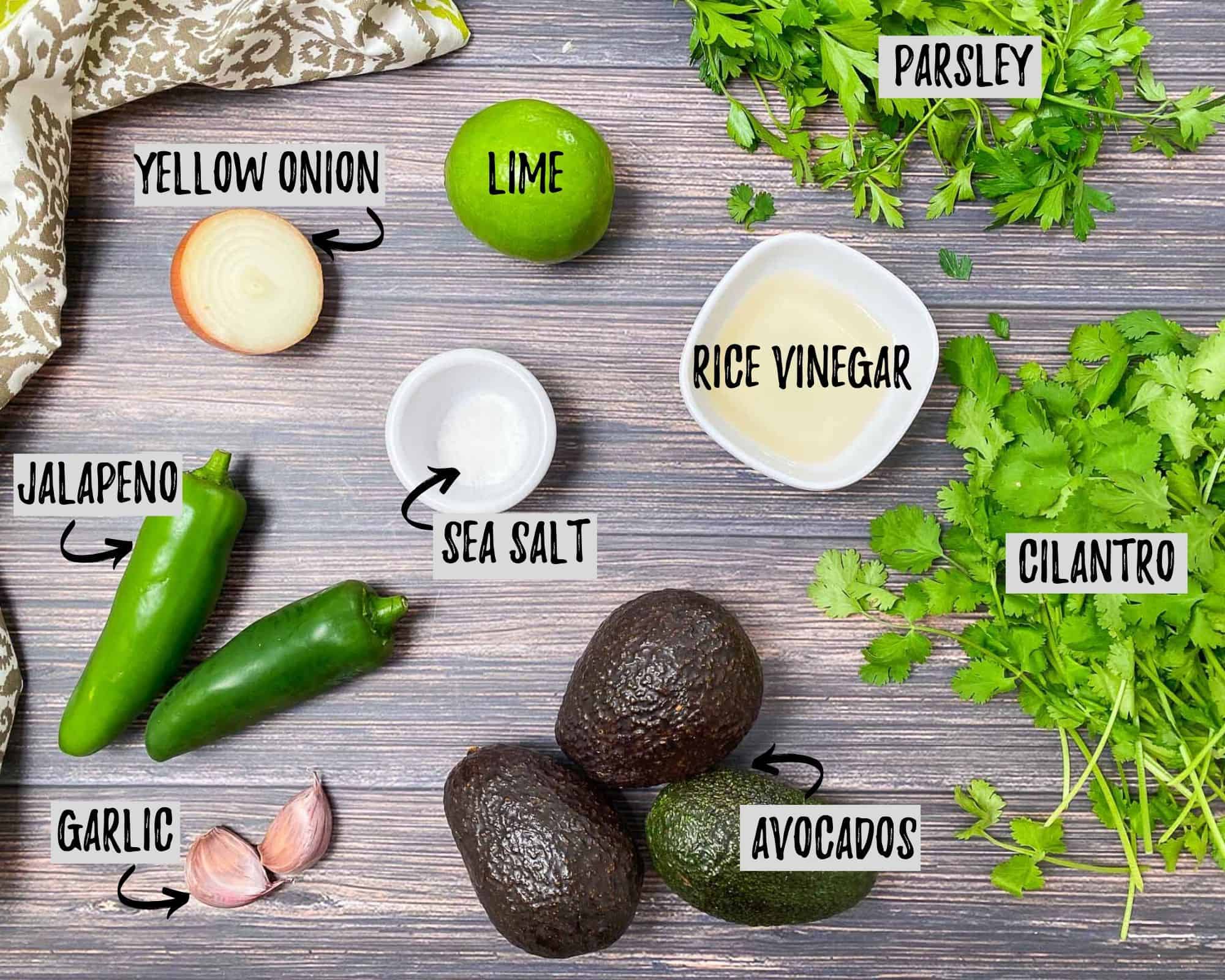 avocados, jalapeno, onion, lime, cilantro, parsley, garlic, salt and vinegar on brown deck