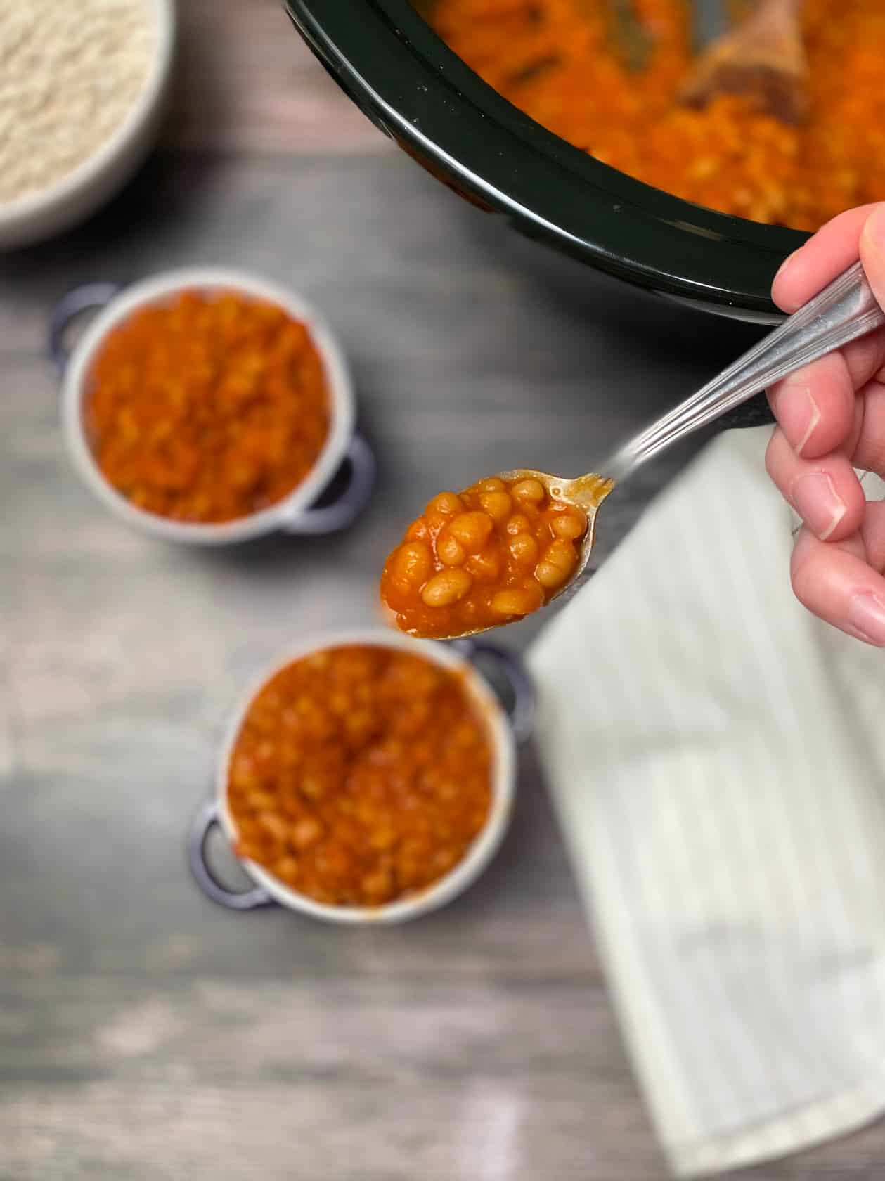 spoon picking up a bite of baked beans from a purple bowl