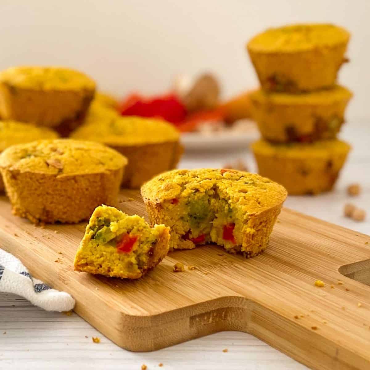 vegan savoury muffin with triangular piece cut out on cutting board.