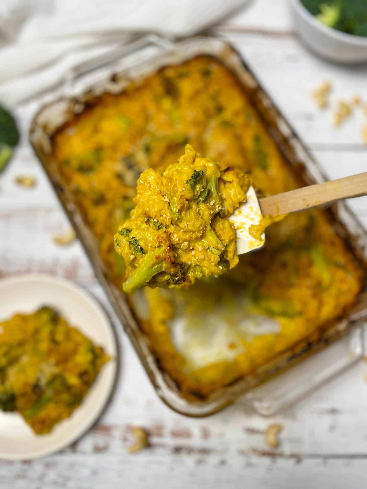 spatula lifting a scoop of broccoli rice casserole from glass baking dish
