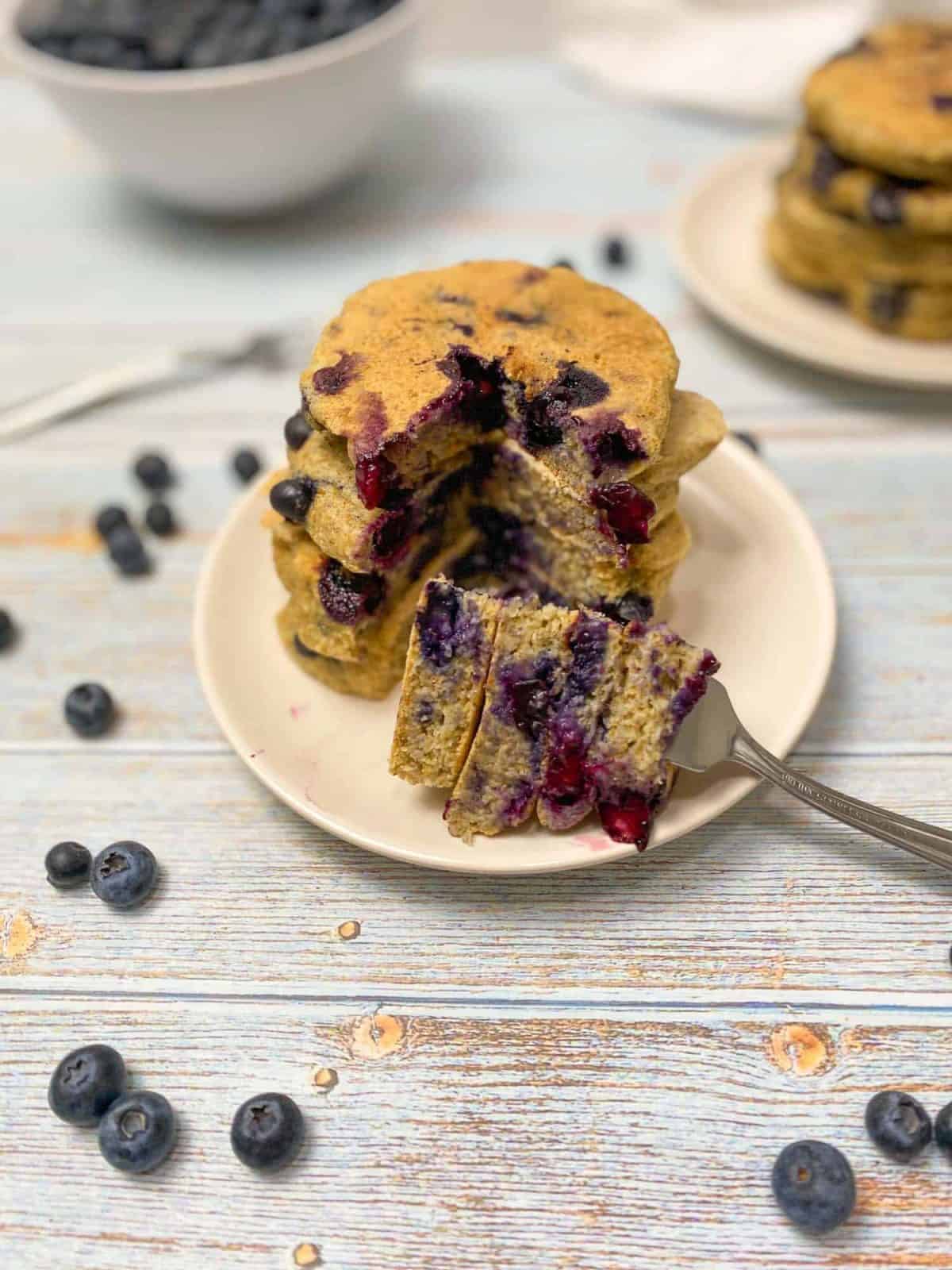 blueberry pancake stack with forkfull of triangle bite cut out
