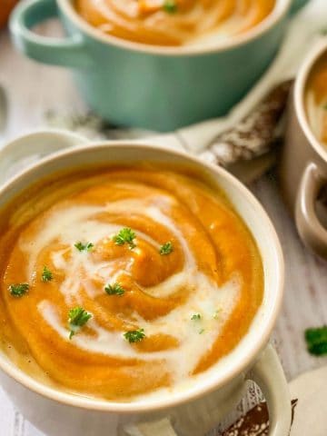 bowls of sweet potato soup garnished with fresh parsley.