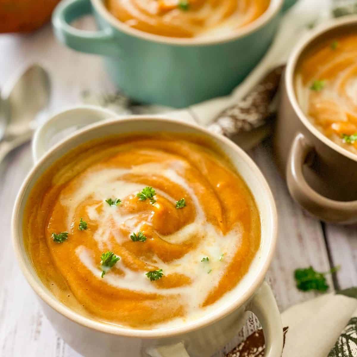 bowls of sweet potato soup garnished with fresh parsley.