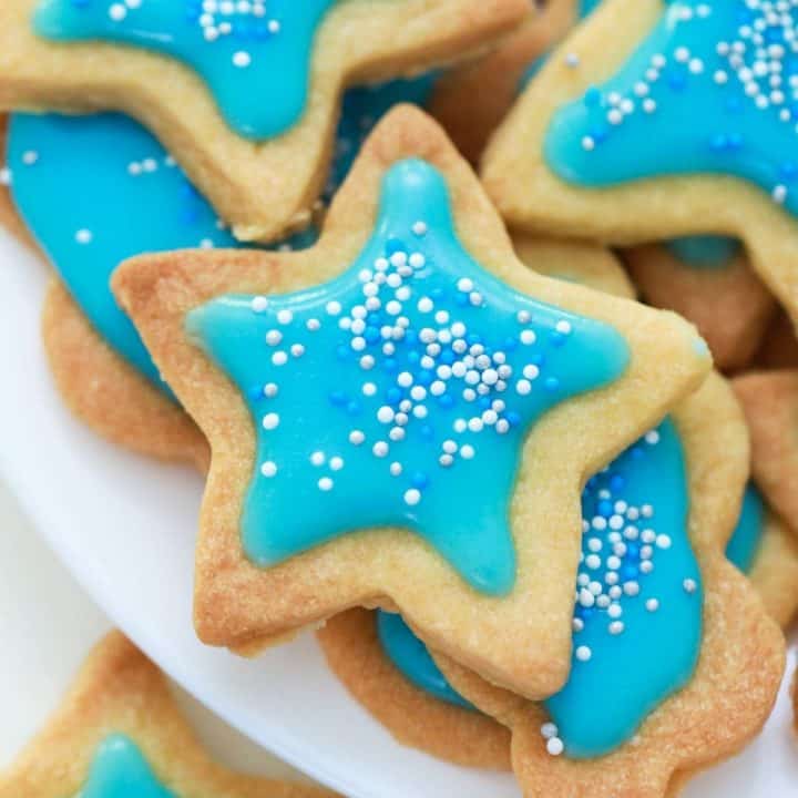 Close up of star shaped cookie with blue icing and sprinkles on top.
