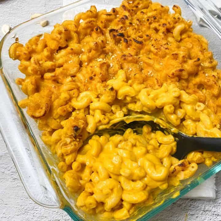 serving spoon scooping out mac and cheese from baking dish