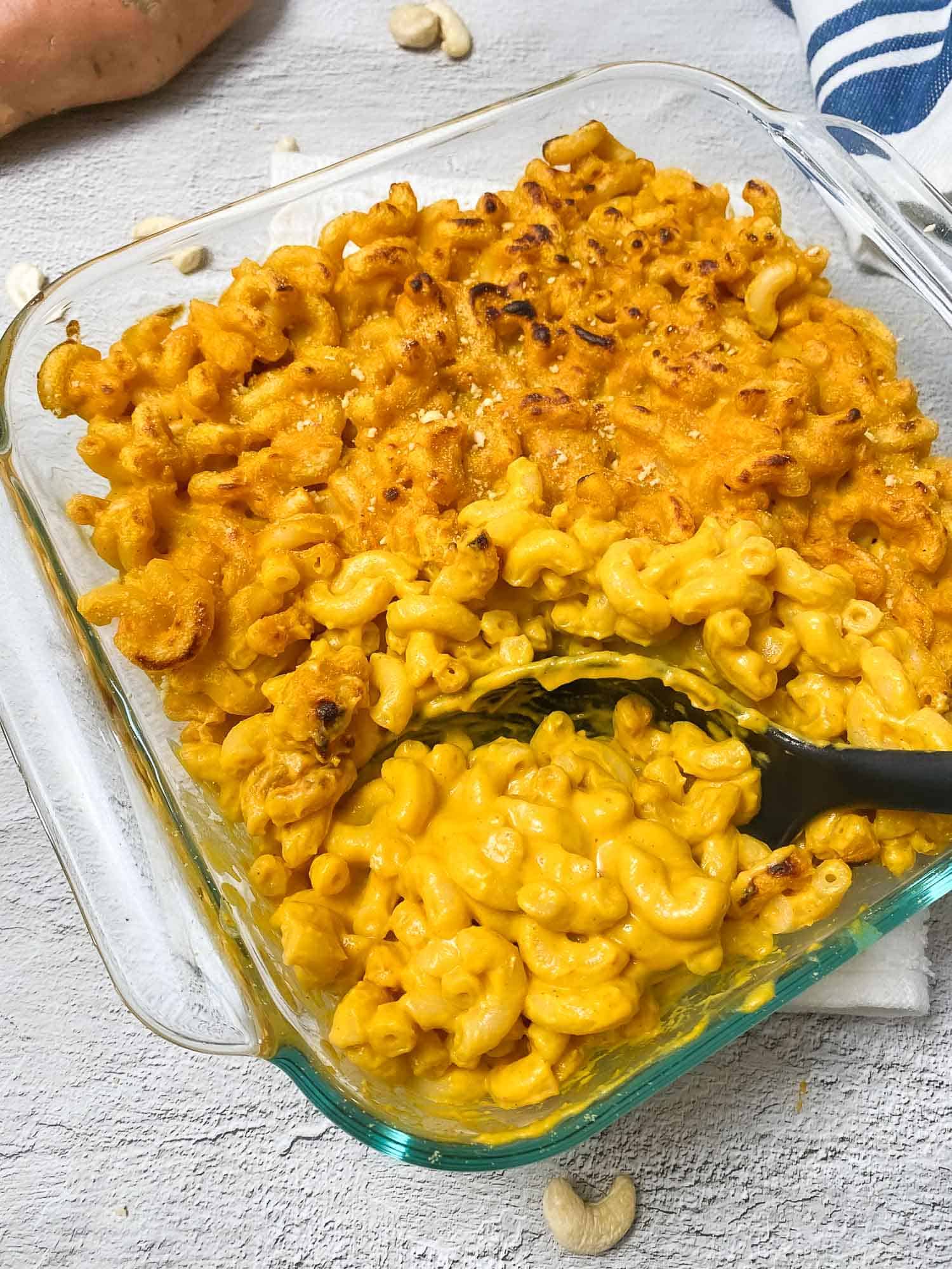 serving spoon scooping out mac and cheese from baking dish