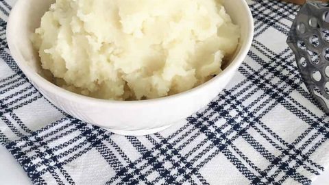 mashed potatoes in bowl with rosemary garnish