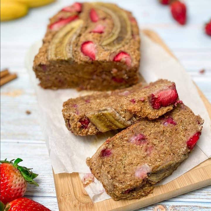 strawberry banana bread on cutting board with two slices cut