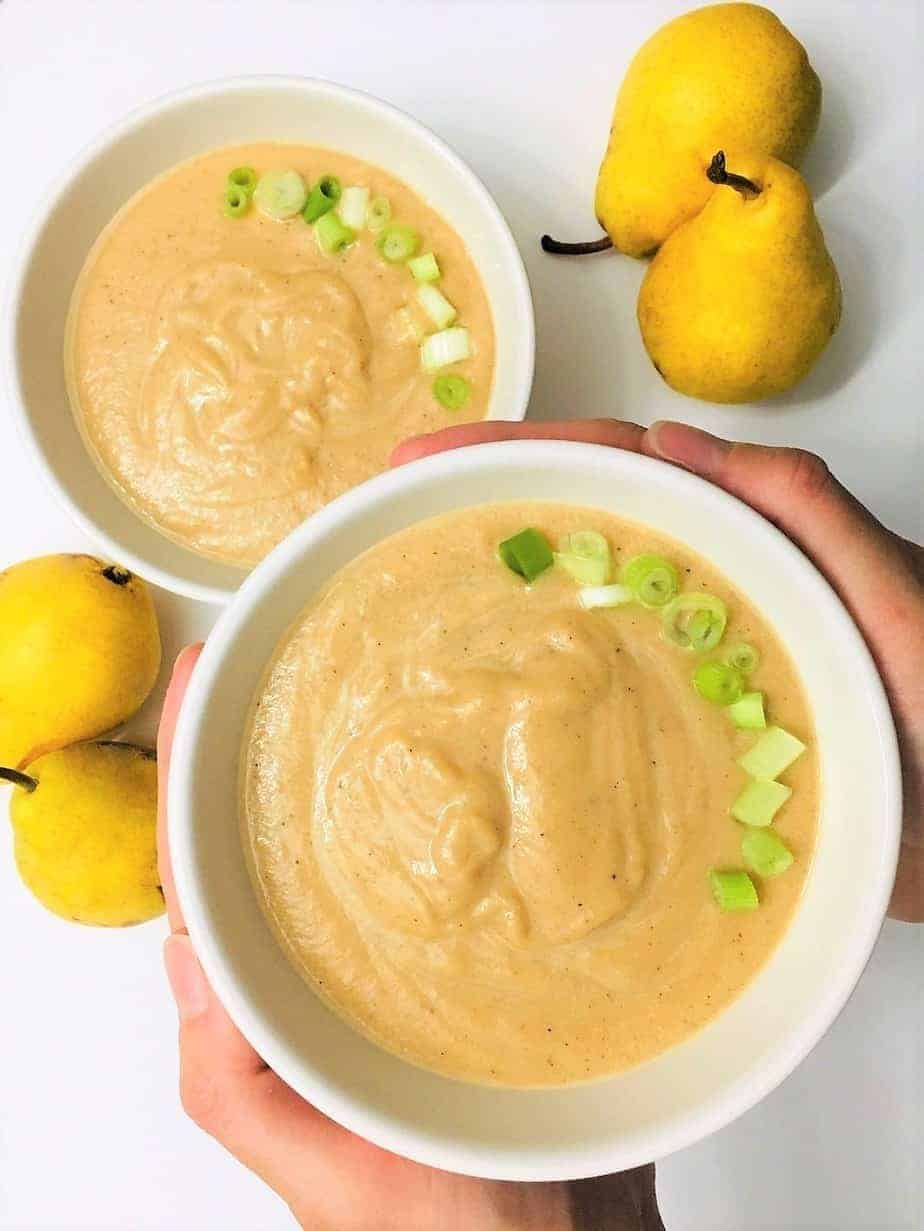 cold vegan pear soup in bowl being held up with hands