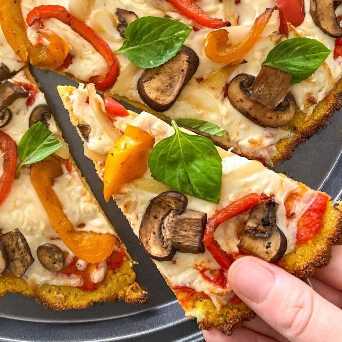 Hand grabbing slice of pizza from pizza tray.