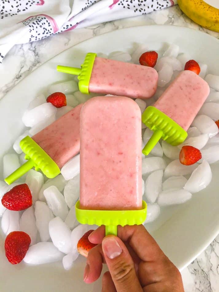 hand holding popsicle with tray in background
