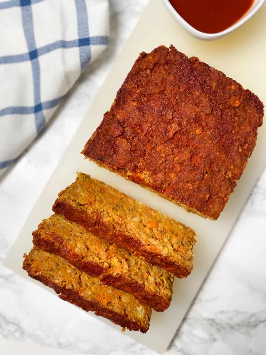 chickpea meatloaf on cutting board with three slices cut and leaning forward