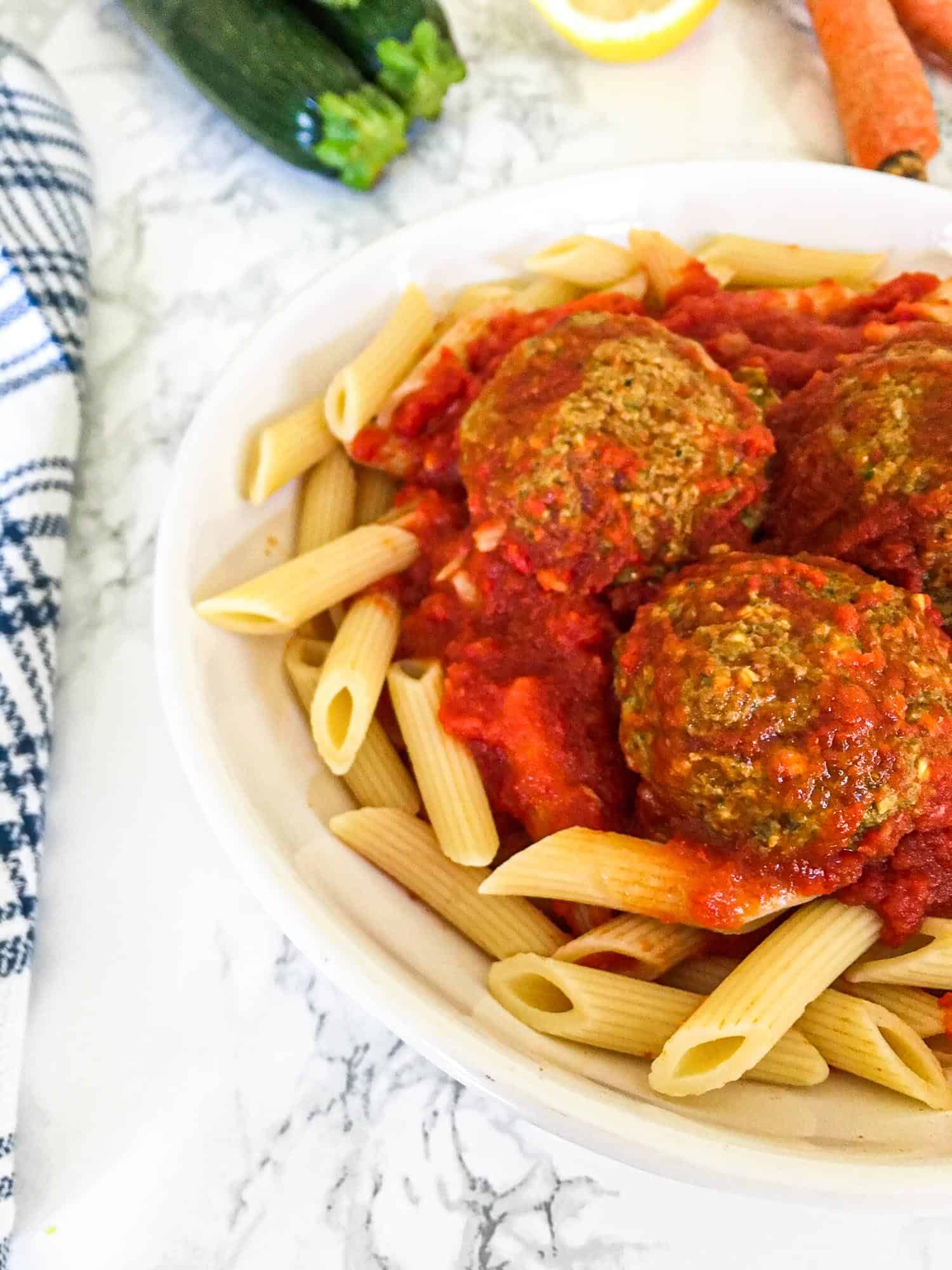 pasta and vegan meatballs in plate with marinara sauce on top