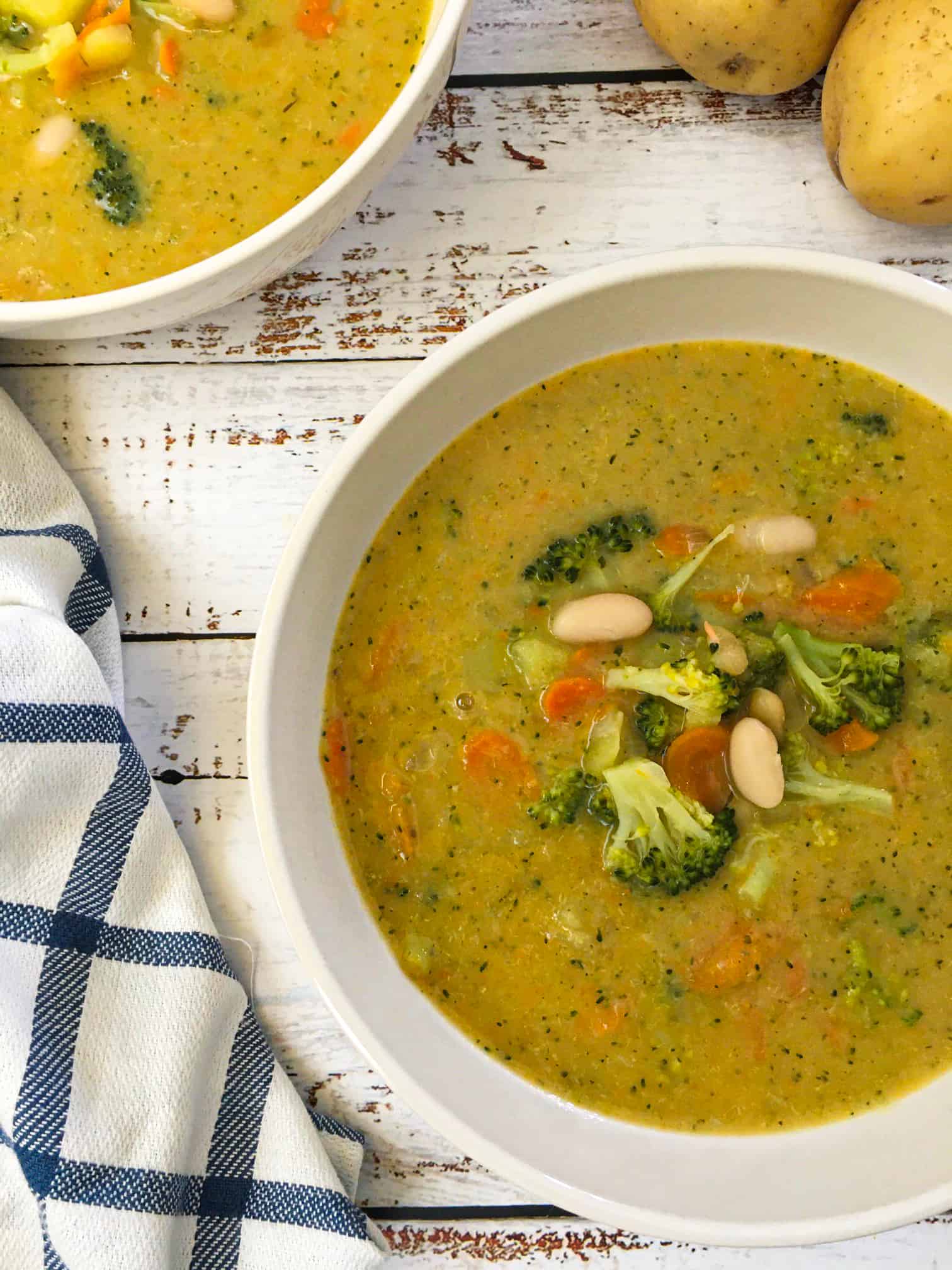 bowl of broccoli potato soup with broccoli, carrot and white bean garnish