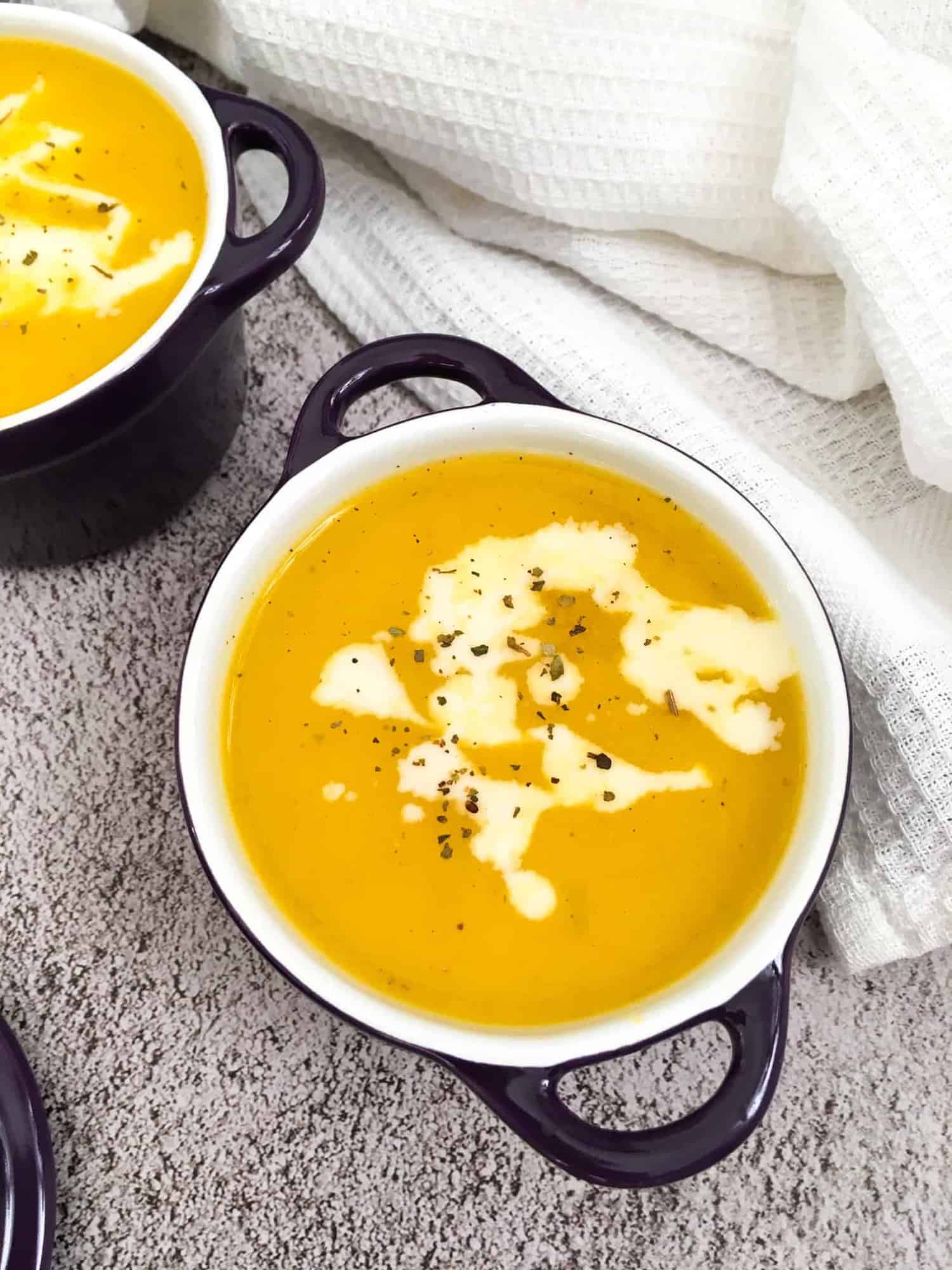 vegan butternut squash soup in bowl with cream garnish.