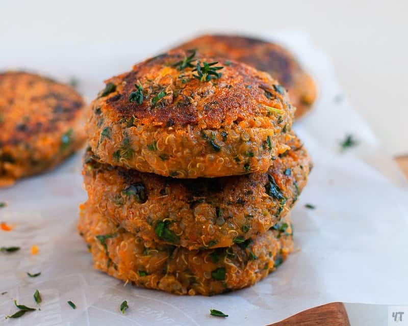 Three sweet potato patties in a stack with green herbs garnished on top.