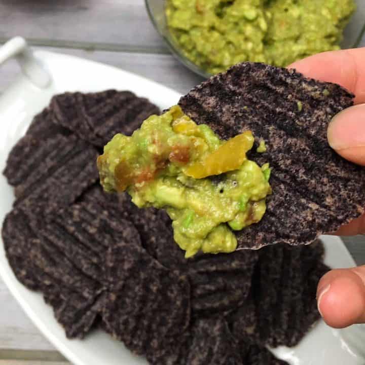 black bean chip in hand dipped in guac
