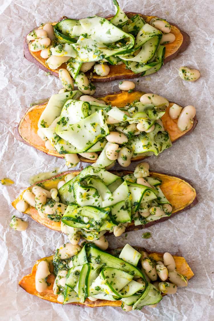Four sweet potato toasts with herbed beans and ribboned cucumber on top.