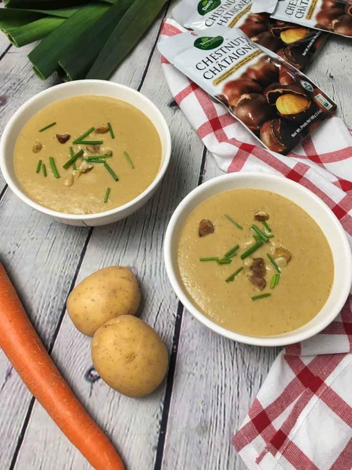 two bowls of chestnut soup with chives and chestnut garnish over top