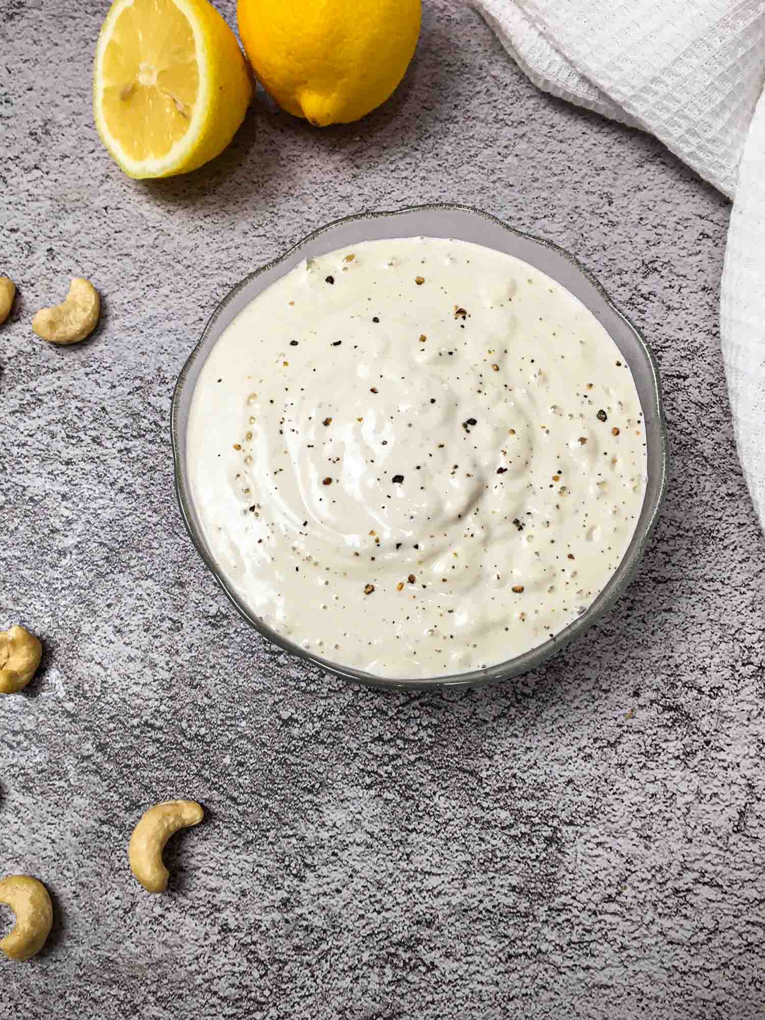 vegan alfredo sauce in glass bowl with cashews scattered around