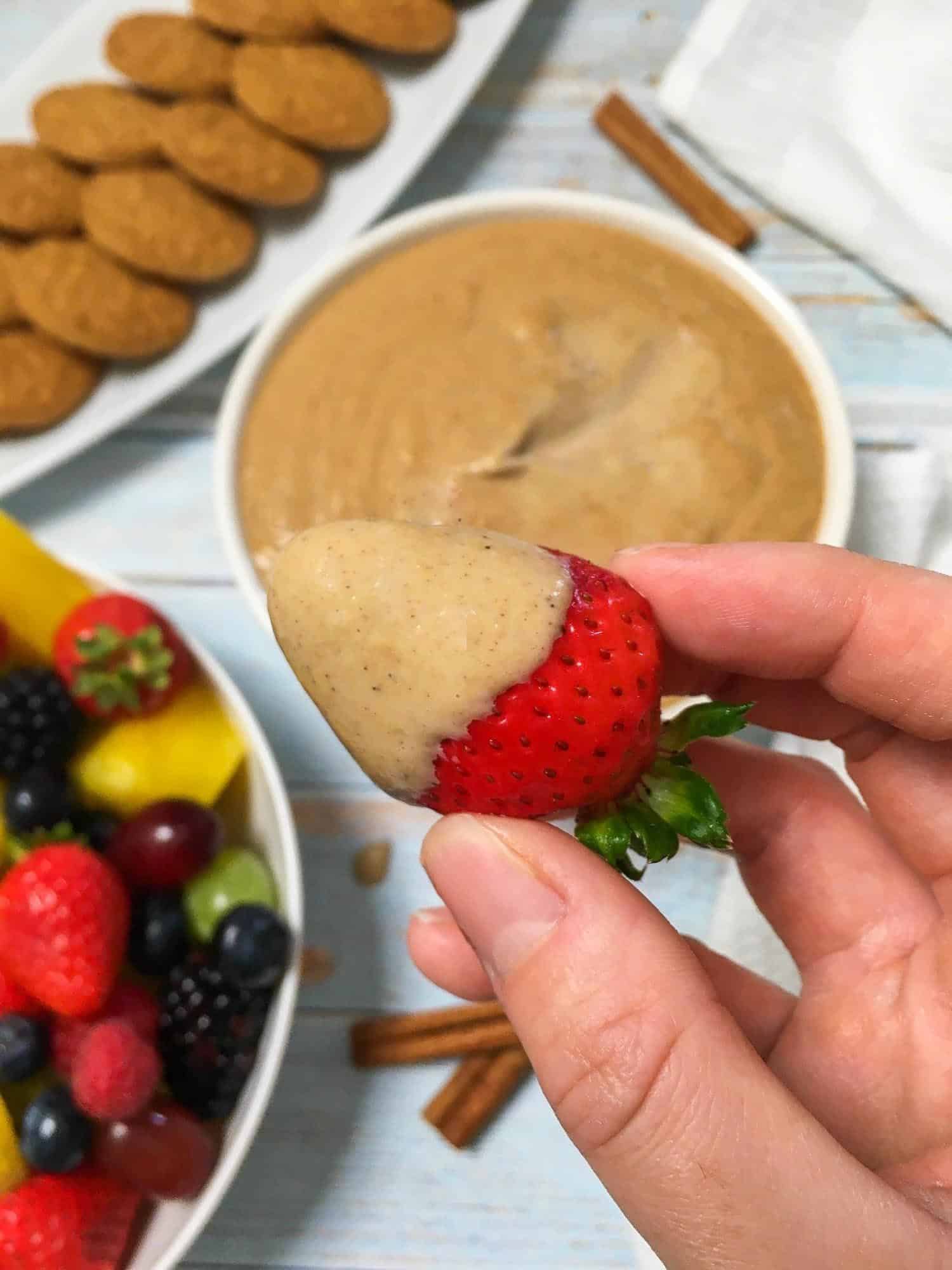 hand holding strawberry dipped in cheesecake dip