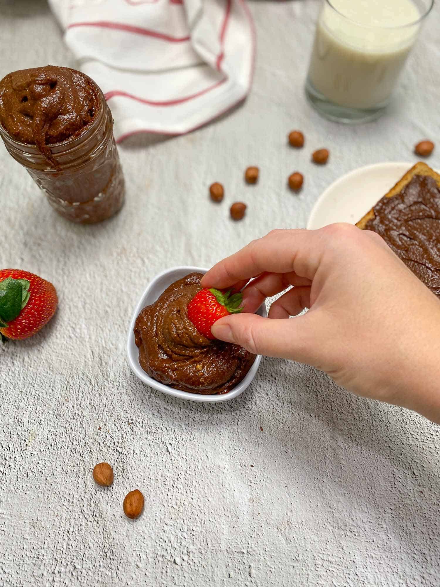 hand dunking strawberry into homemade nutella