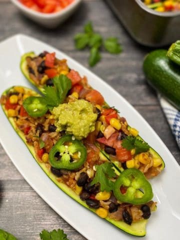 Two zucchini halves stuffed with beans, rice, veggies and guacamole.