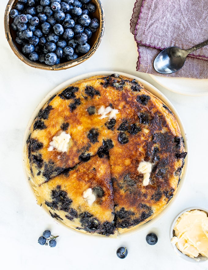 giant blueberry pancakes on platter with one triangular slice cut out