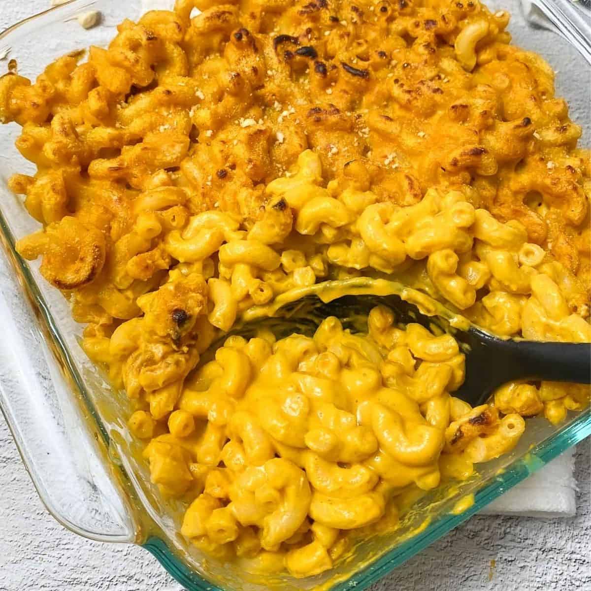 serving spoon scooping out mac and cheese from baking dish