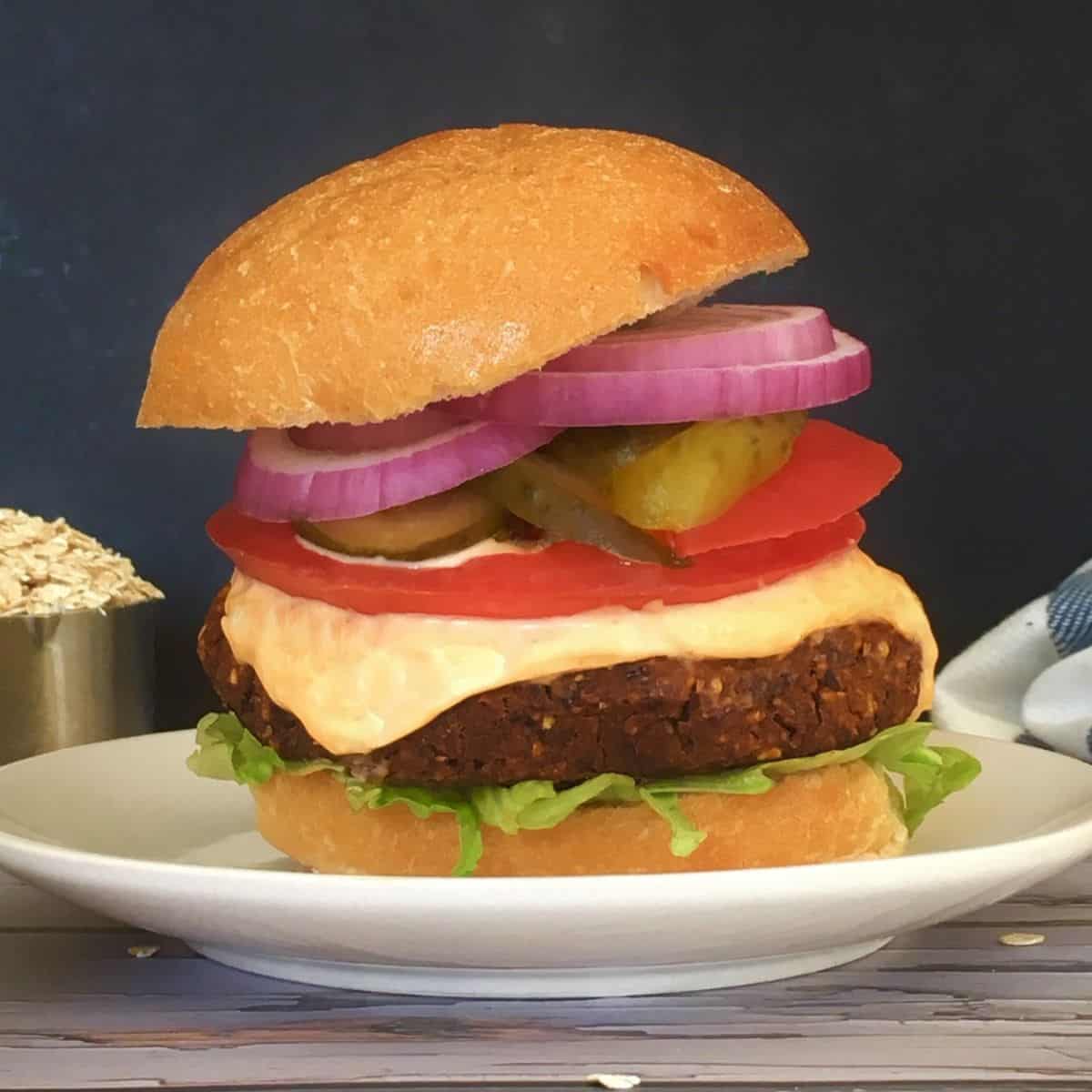 Burger in bun with tomato, onion, pickle, spicy mayo