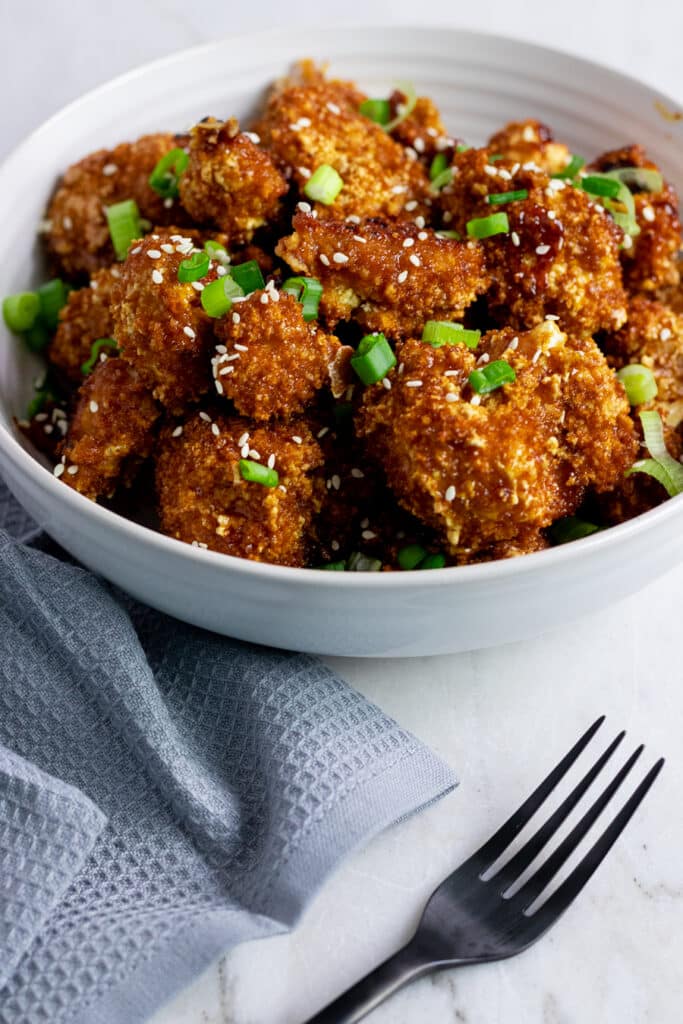 breaded cauliflower bites in white bowl garnished with chives
