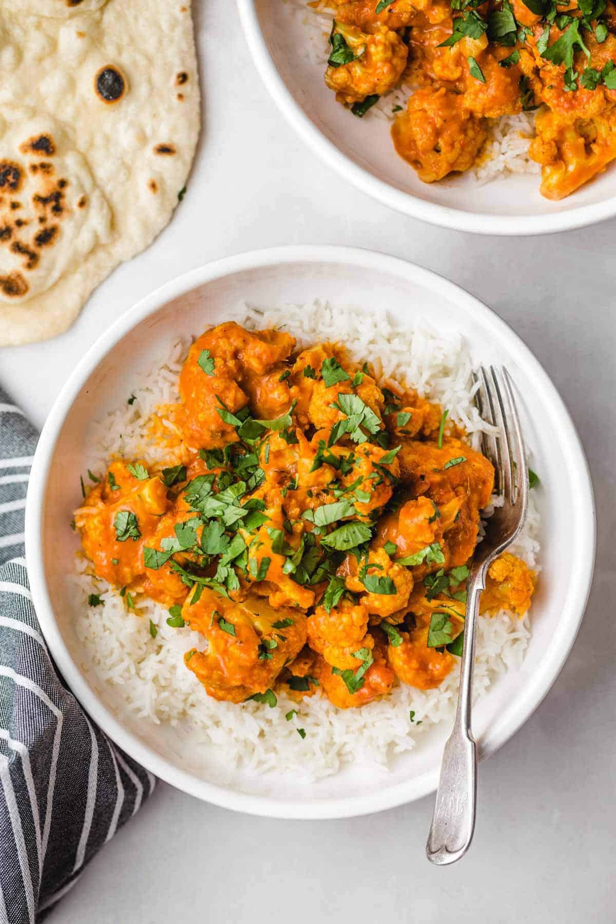 butter chicken cauliflower on bed of rice in white bowl