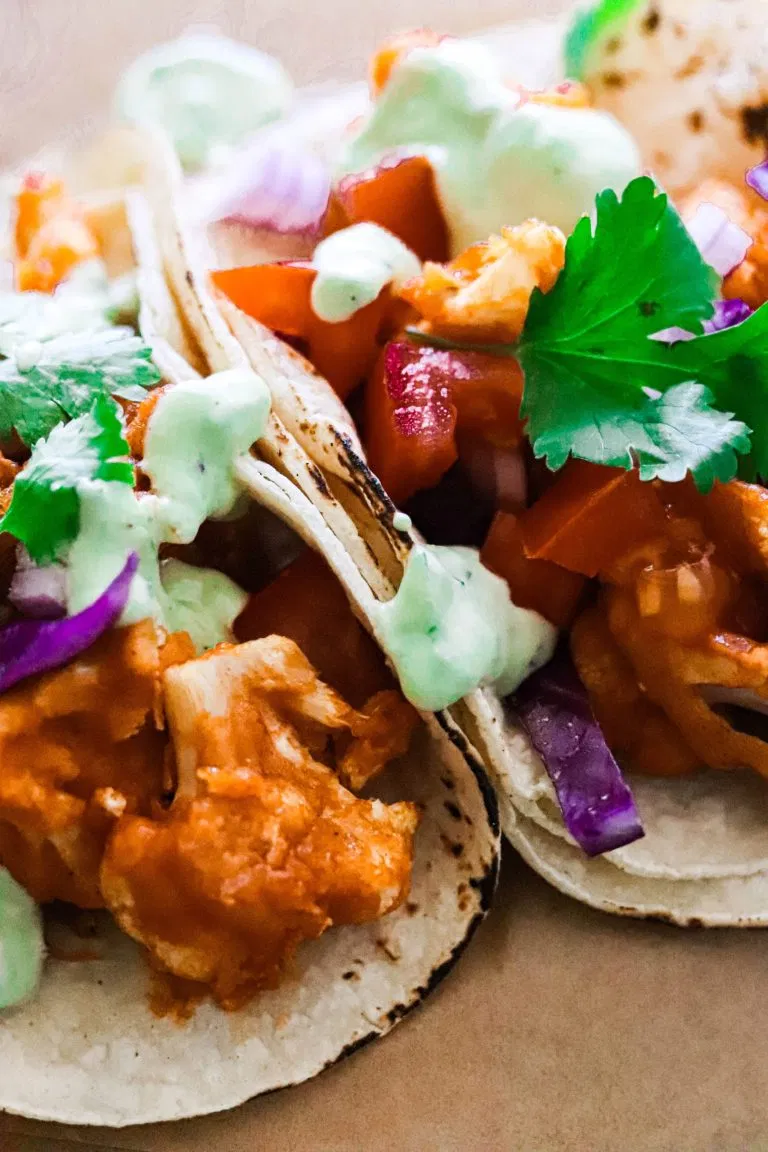 buffalo cauliflower in tacos with slaw and cilantro on top