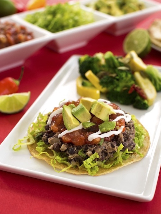 tostada with lettuce, black beans, salsa and avocado on top