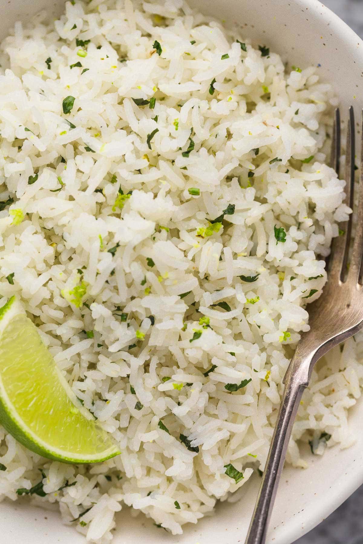white bowl of rice with fork inside and lime wedge