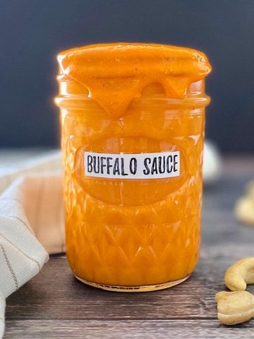 glass jar filled with homemade orange hot sauce labeled Buffalo sauce
