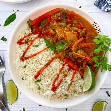 white bowl with rice, thai curry and drizzled in hot sauce