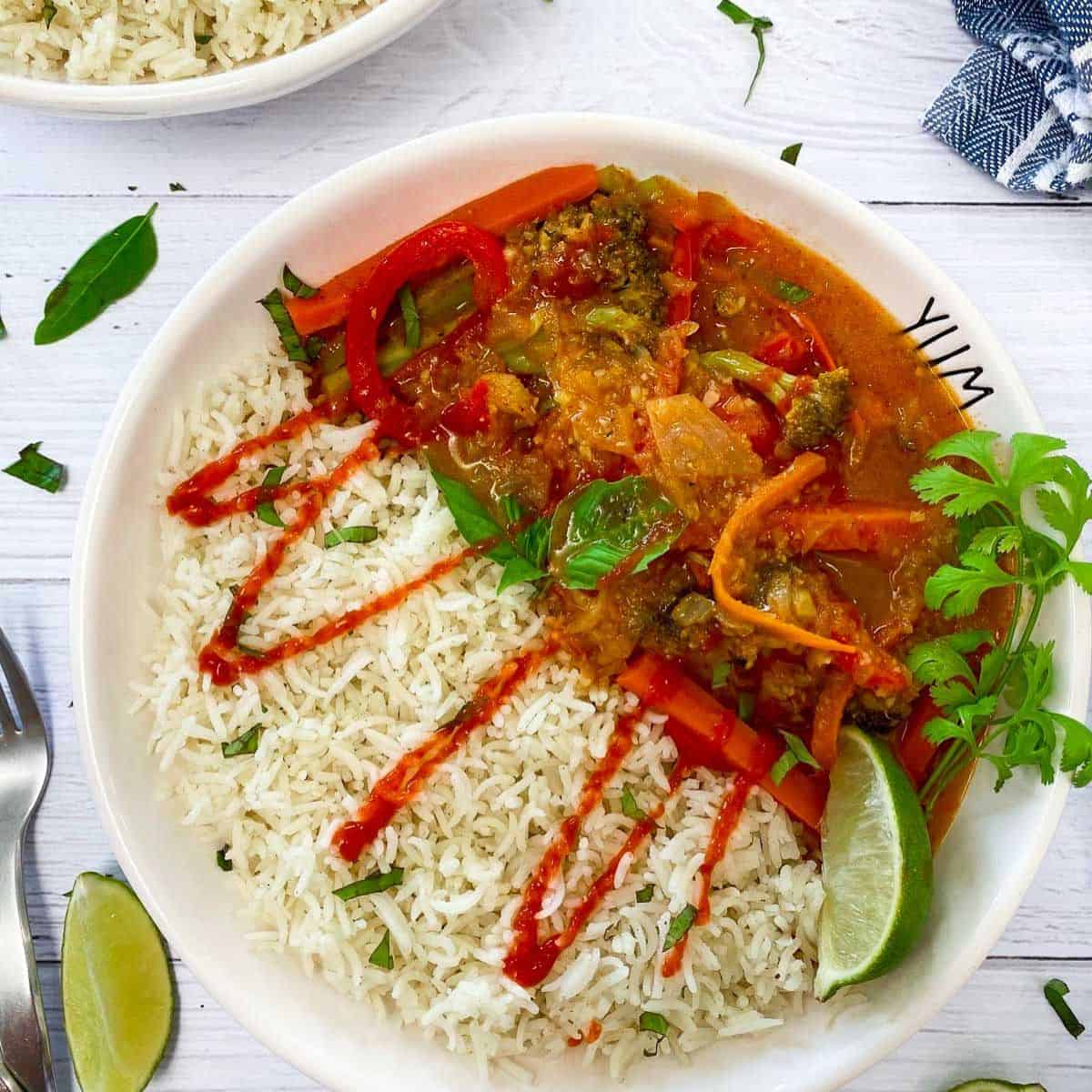 white bowl with rice, thai curry and drizzled in hot sauce